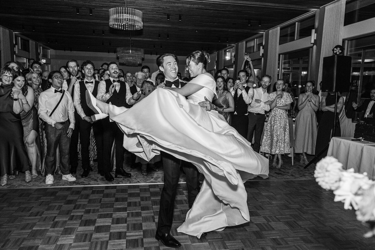 Groom lifting his bride with her dress flying behind her during their first dance as newlyweds at The Marion, Canberra ACT