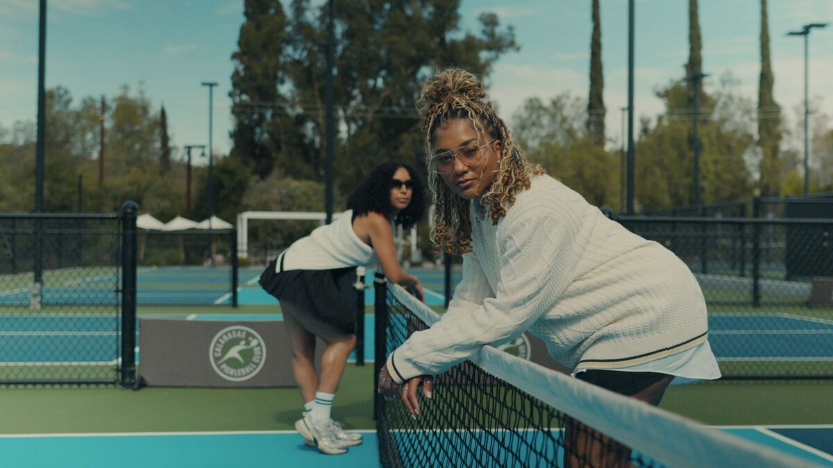 two women on a tennis court leaning over the net.