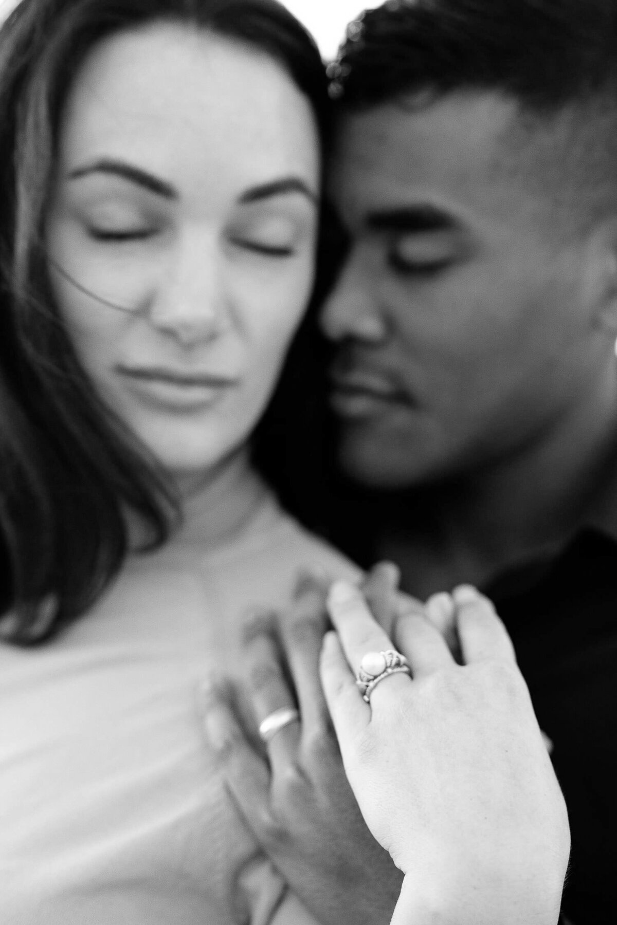 Engagement rings in focus and couples faces blurry in the background