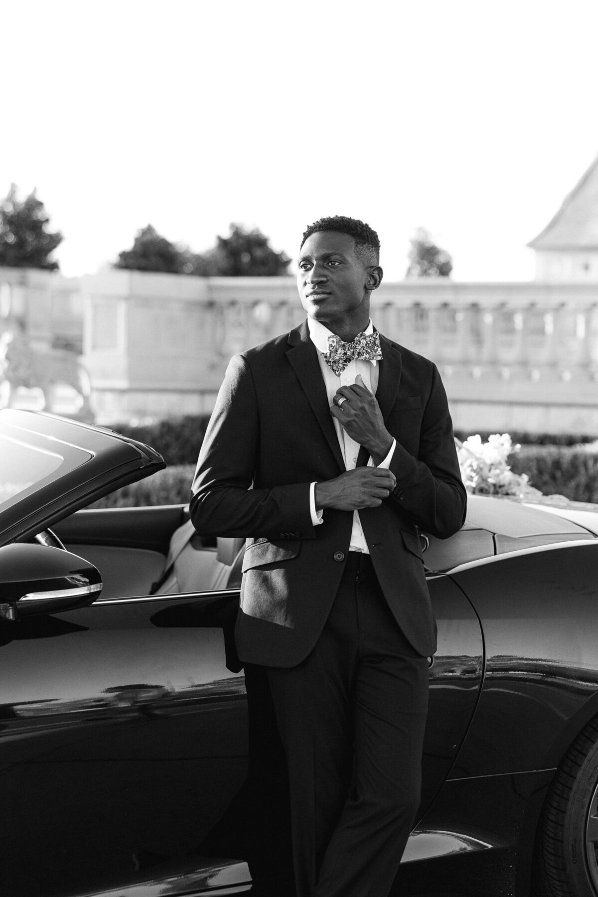 a groom posing by a sports car