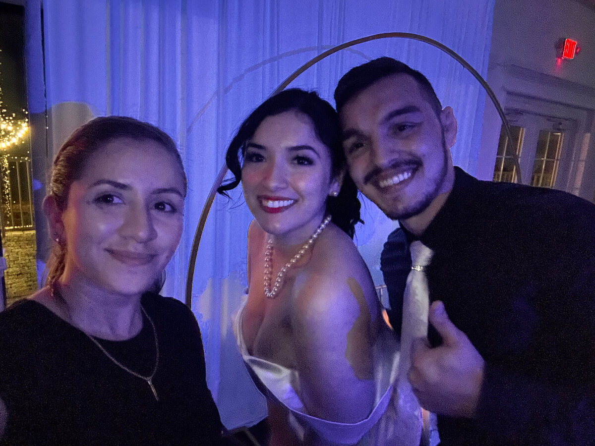 Female wedding photographer posing with newlyweds during their reception at The Royal Crest Room in St. Cloud, Florida.