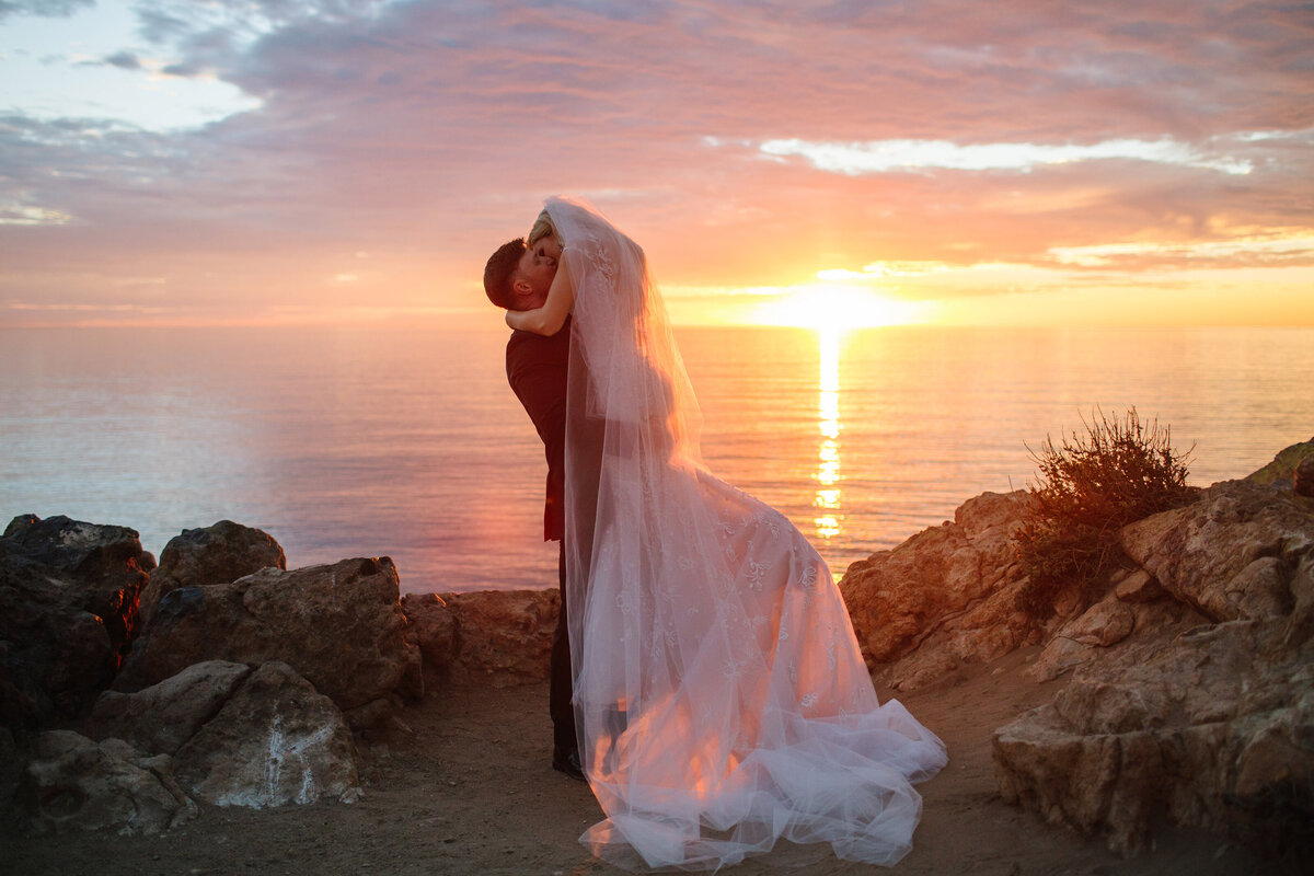 bride and groom kiss during sunset