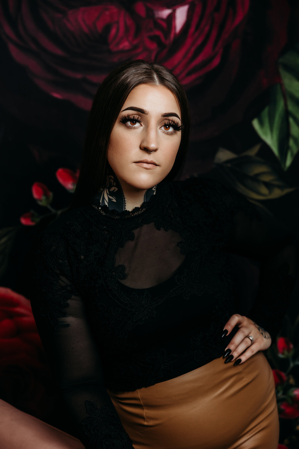Headshot portrait of woman taken in front of floral backdrop.