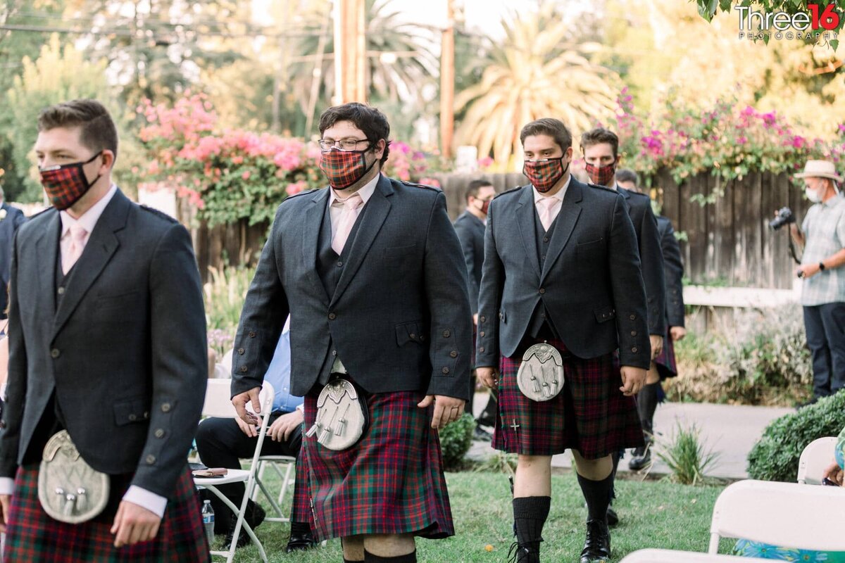 Groomsmen walk into the ceremony wearing kilts and Covid masks
