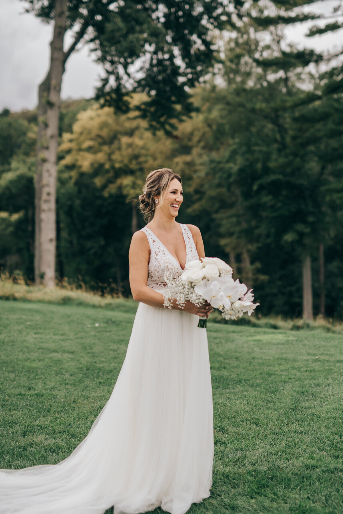 Bride posing for traditional photos with an elegant white wedding bouquet