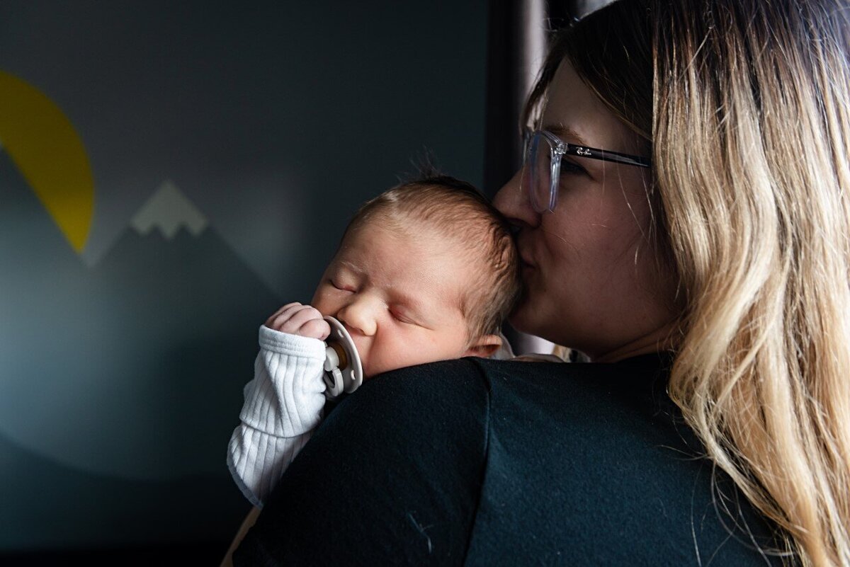 mom kissing newborn boy on head