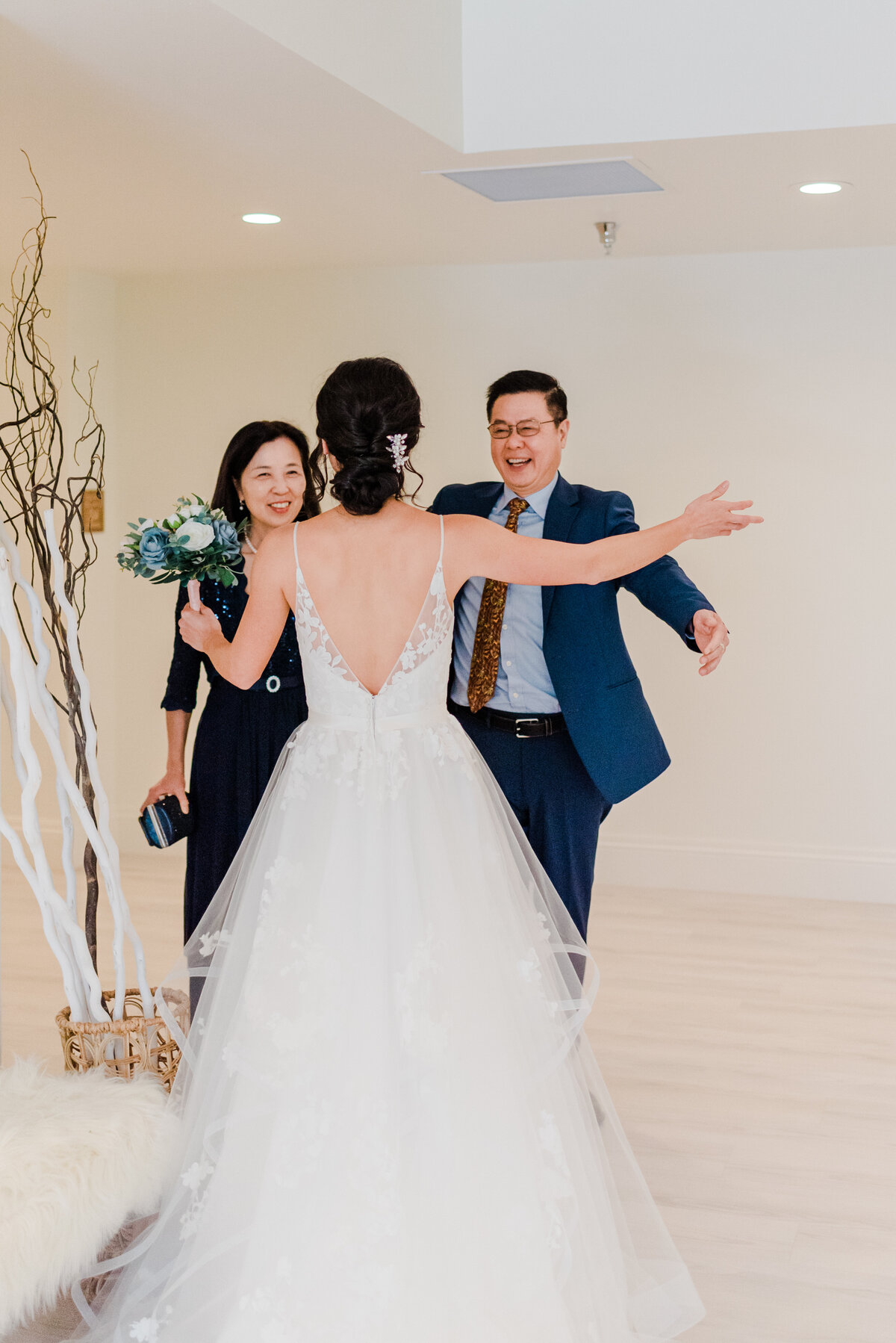 Bride with her back to Denver wedding photographer, hugs her mom and dad as they view her for the first time before the ceremony