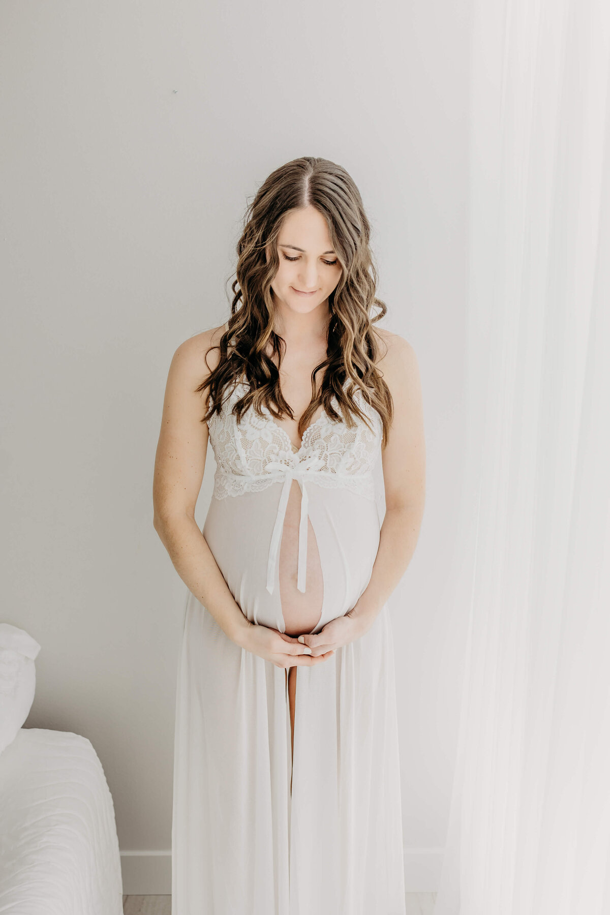 Maternity session brunette woman in white looking down