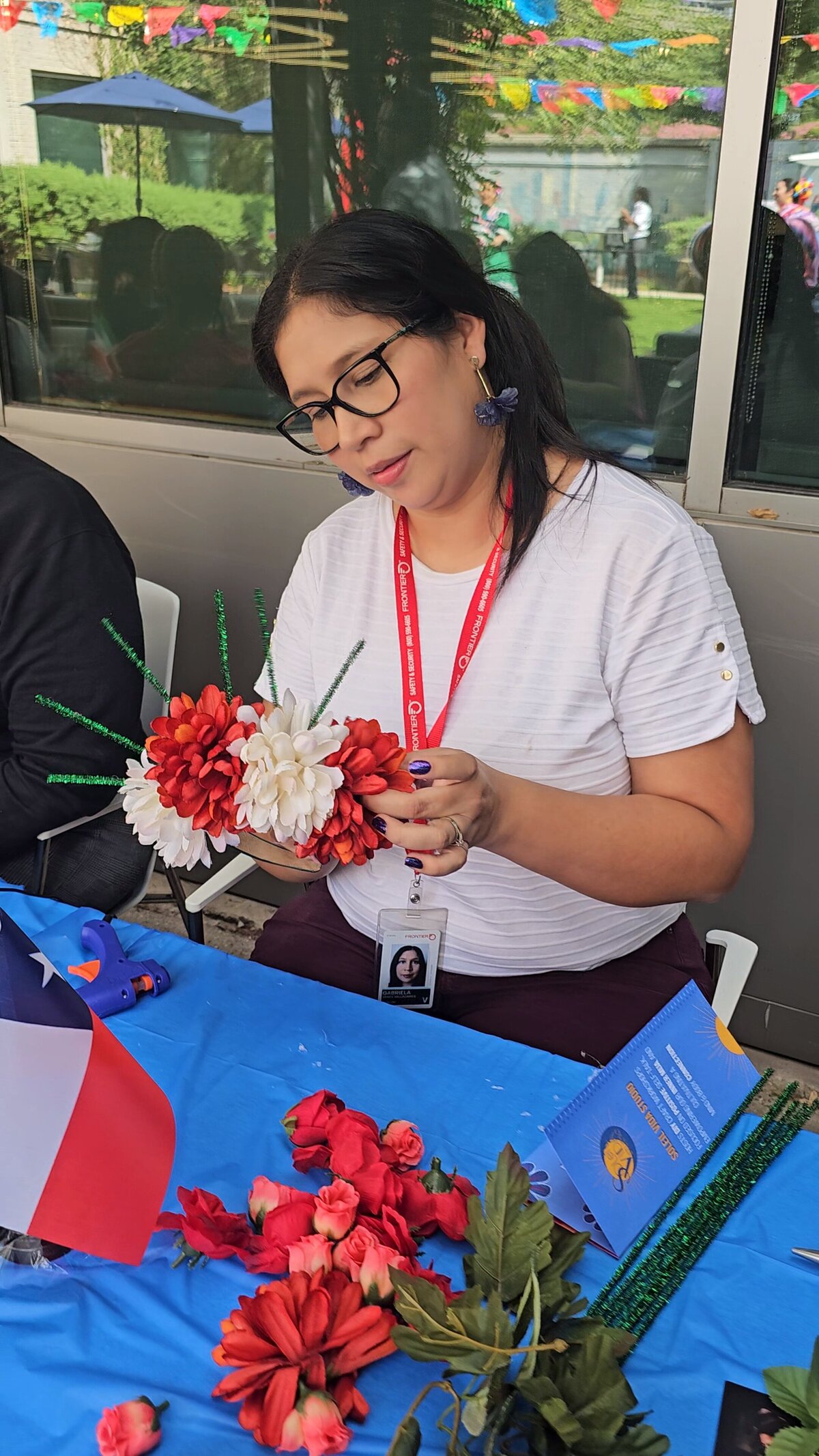 The artistry as a woman dressed in a chic black T-shirt proudly showcases her handcrafted flower wreath in our art workshop. The wreath features an array of colors, a testament to the vibrant creativity nurtured at Soleil Vida Studio.