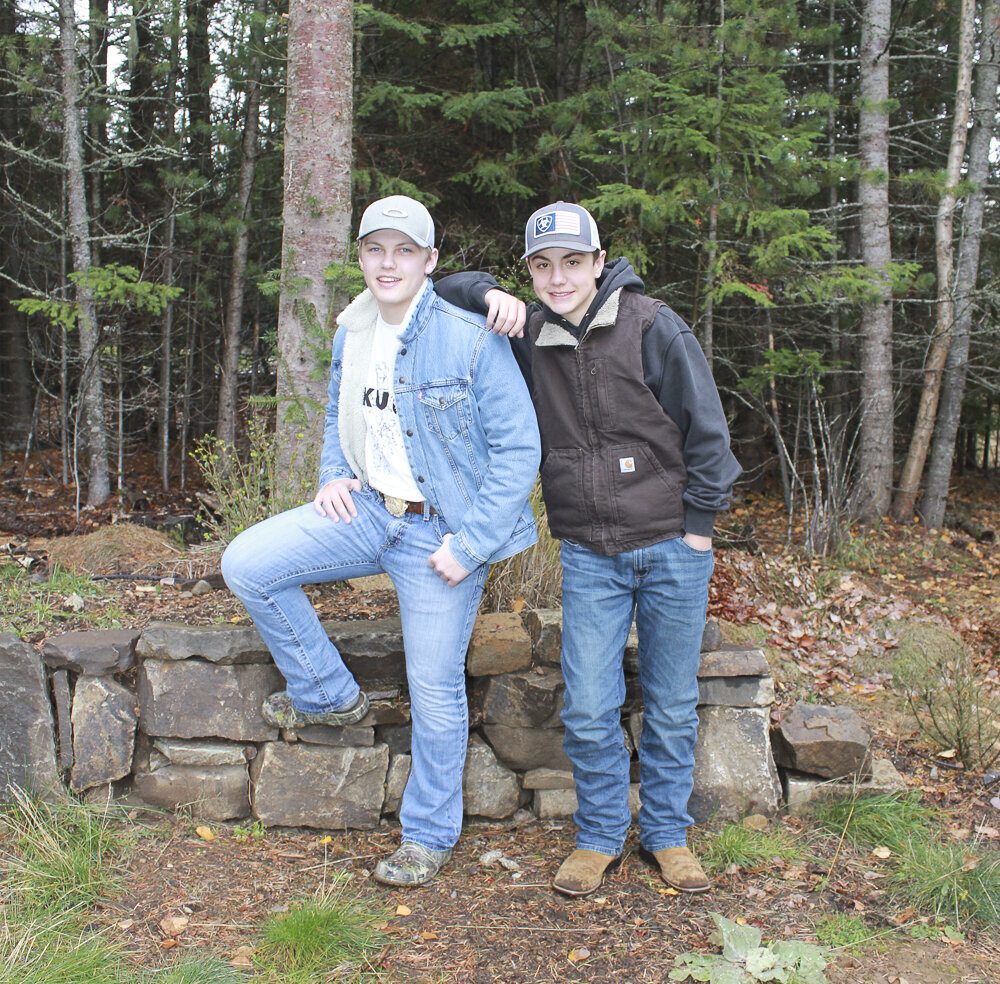 photo of 2 Brothers one leaning on the other in the  forest smiling