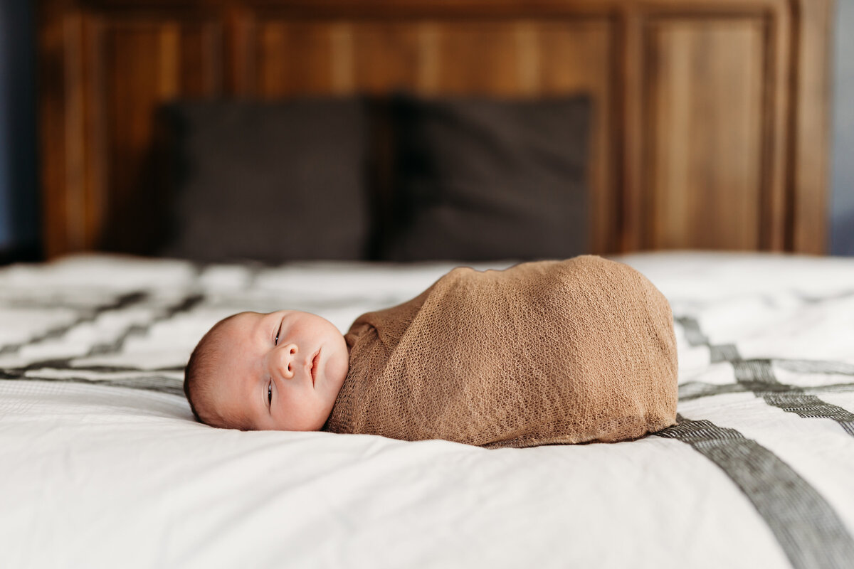 newborn baby swaddled on bed by harrisburg pa newborn photographer