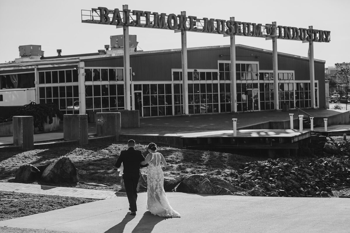 A newlywed couple walking together outside of a museum 