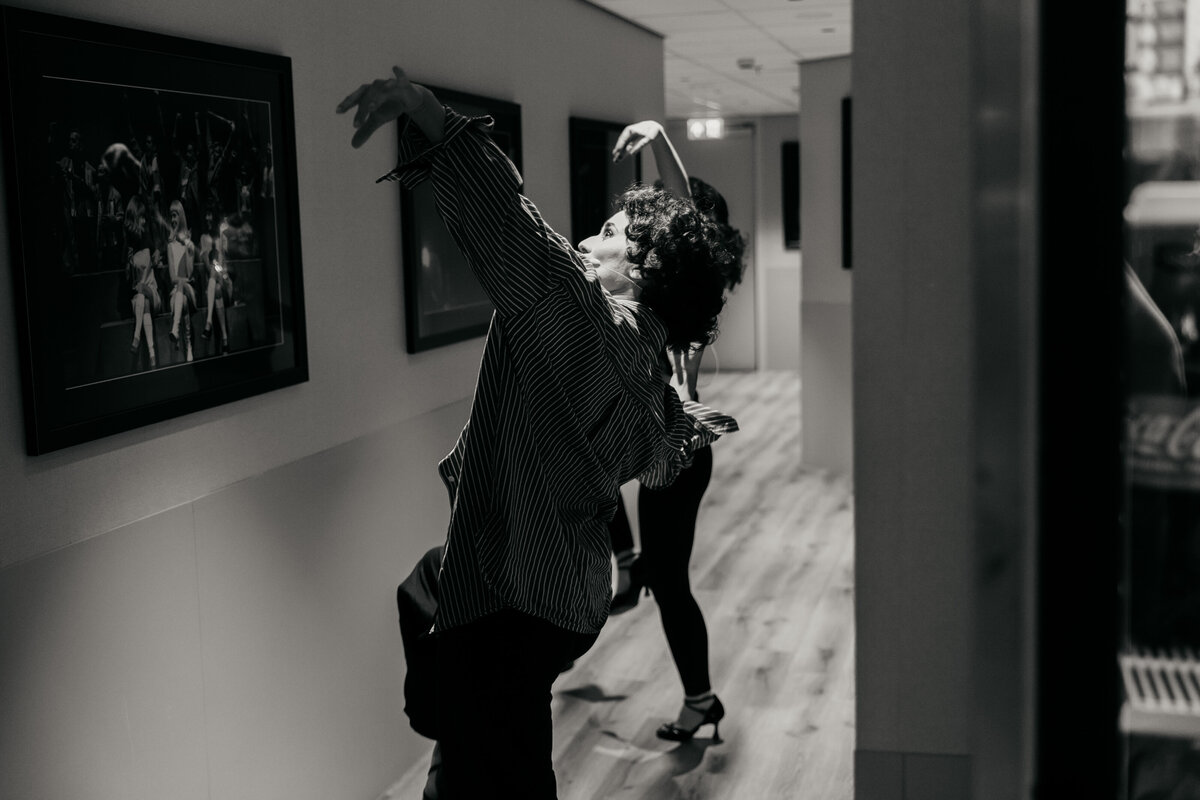 Dansers oefenen hun choreografie in de gang backstage van een theater.