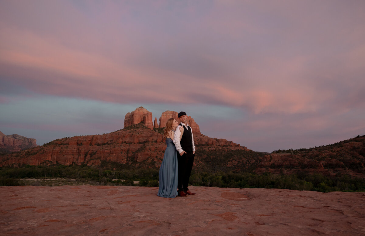 Couple standing against red rock backdrop during Sedona engagement session