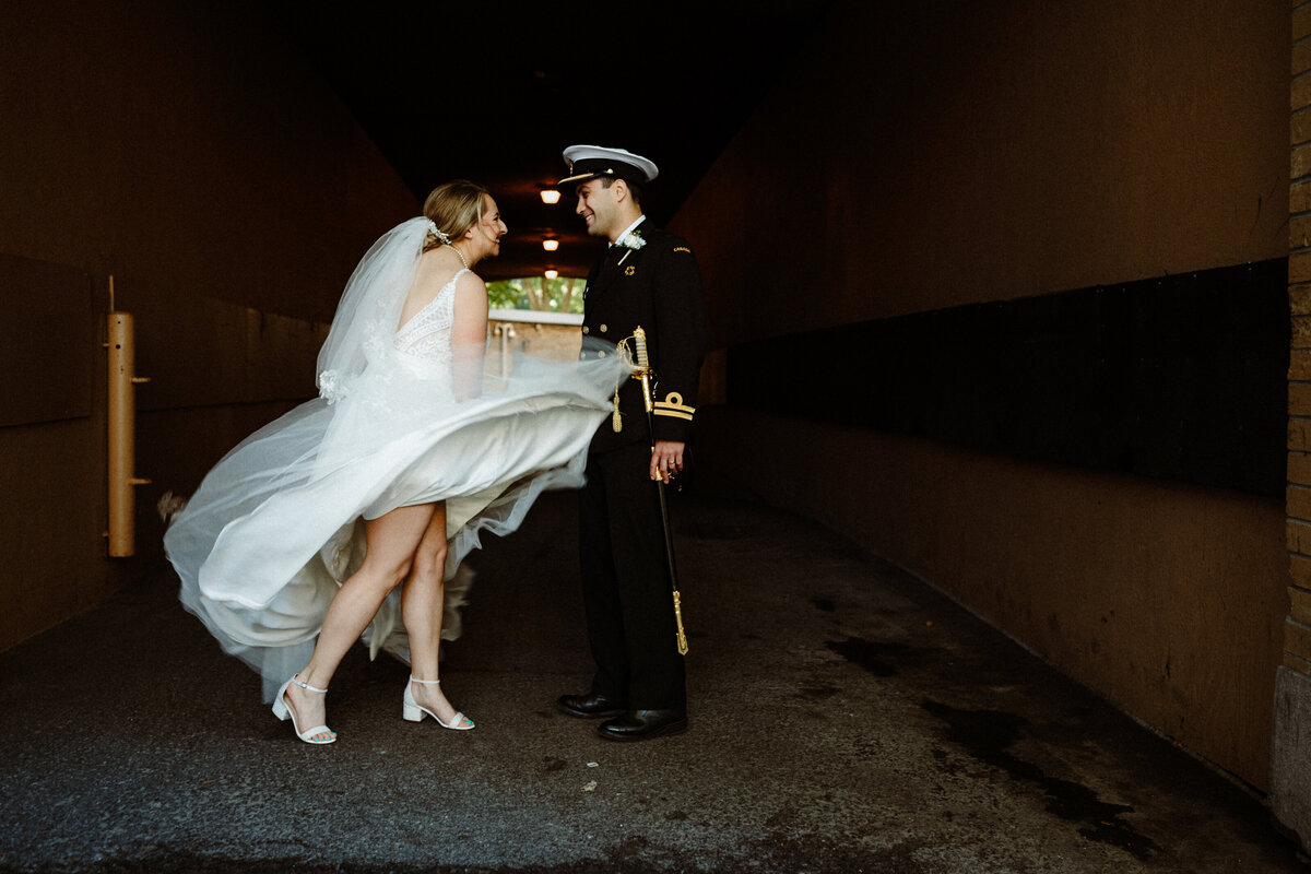 bride playfully playing with her dress in front of her groom