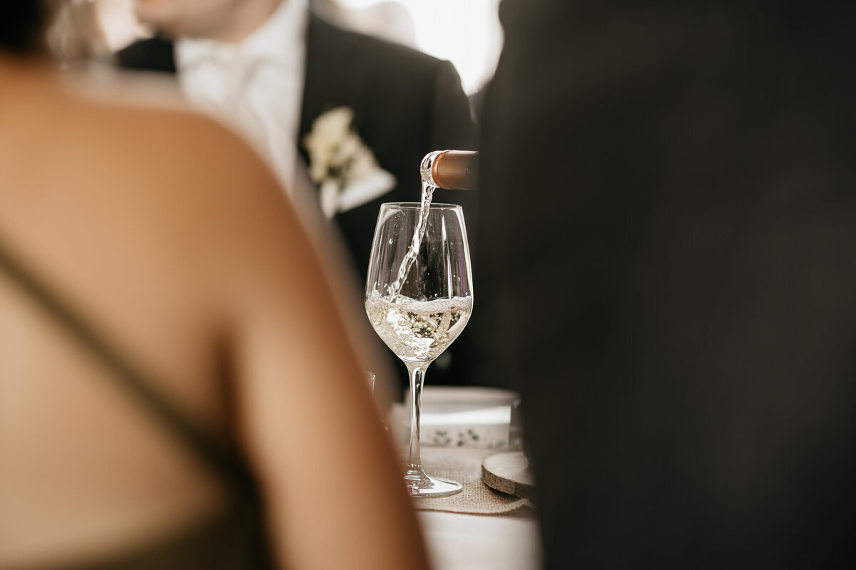 Close-up van een gast met een elegant champagneglas tijdens een feestelijke toast op de bruiloft.