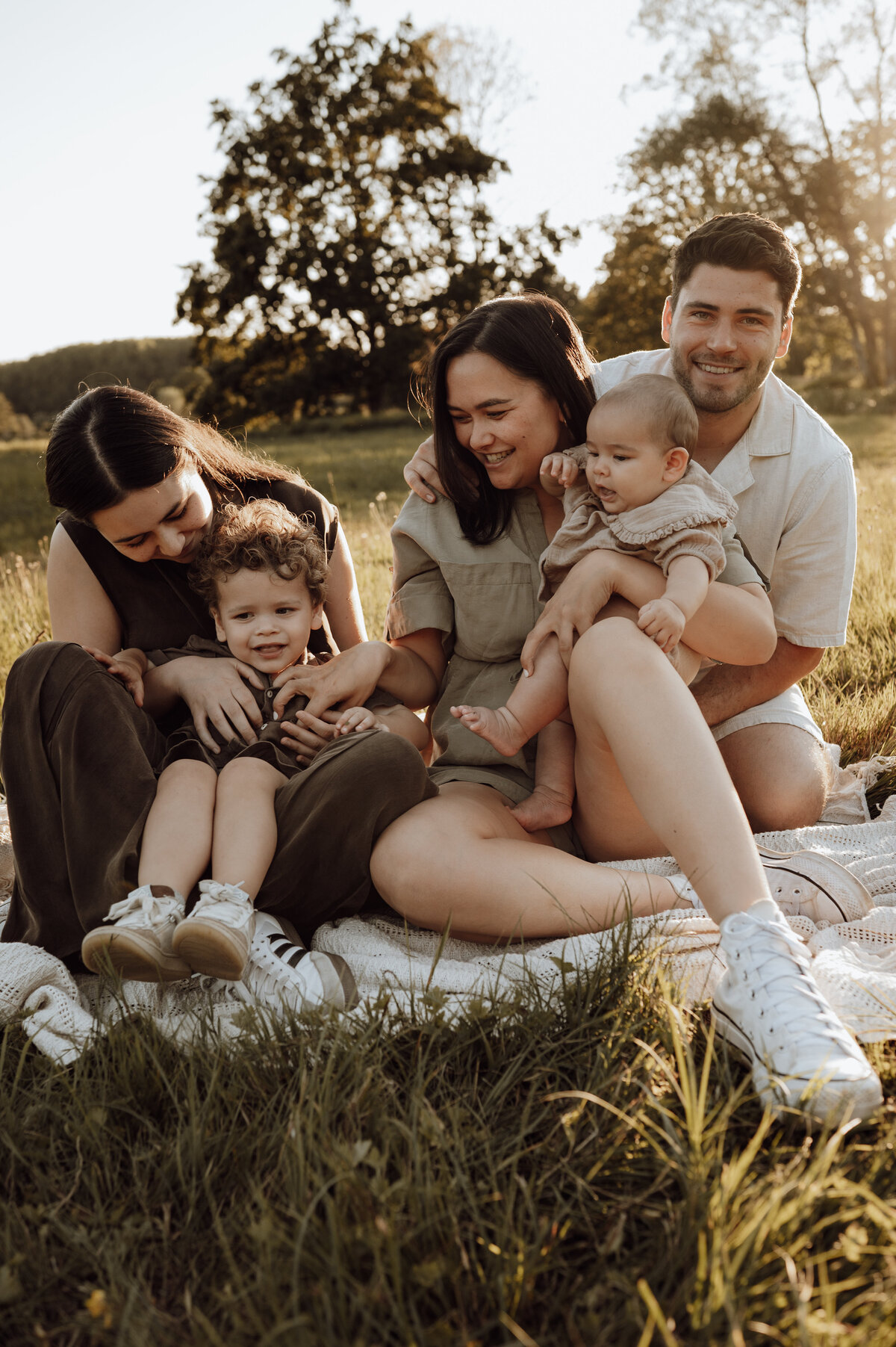 Gezin kijkt elkaar liefdevol aan tijdens familie fotoshoot in het gras