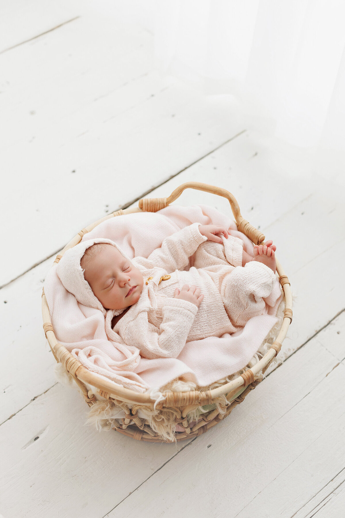 babygirlinbasketwithpalepinkoutfit