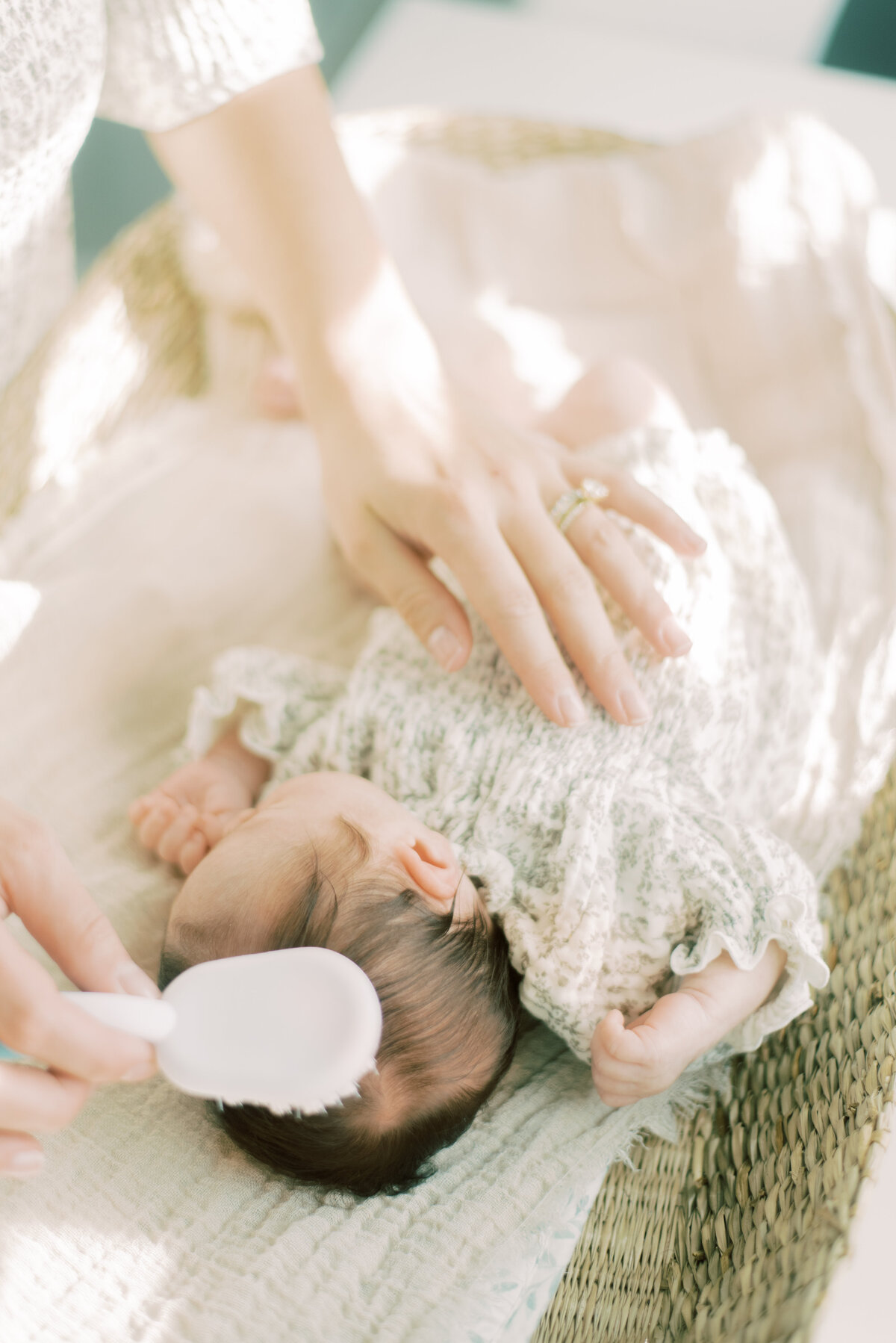 Mother brushing her newborn's hair gently on a changing basket – capturing delicate details of early motherhood