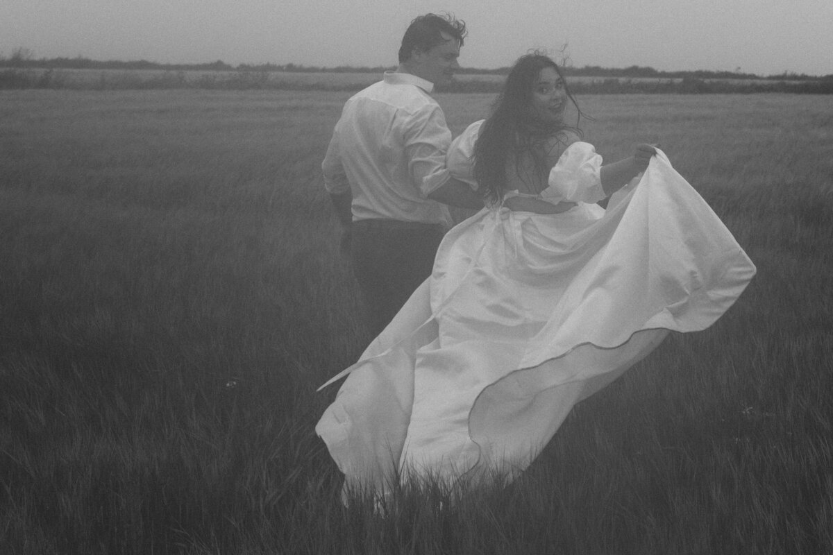 newly maried couple in black and white running in a field