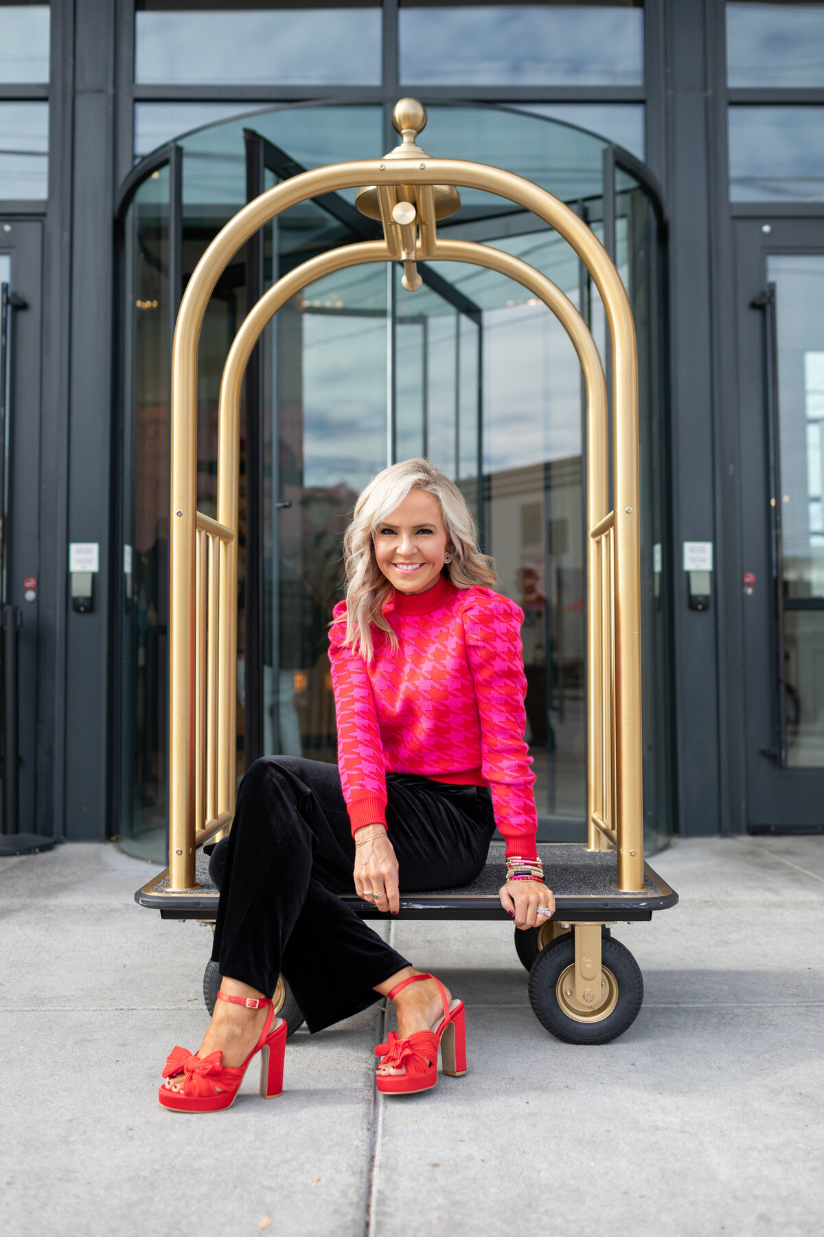 Natasha of Hello Happiness sitting on a bellhop cart