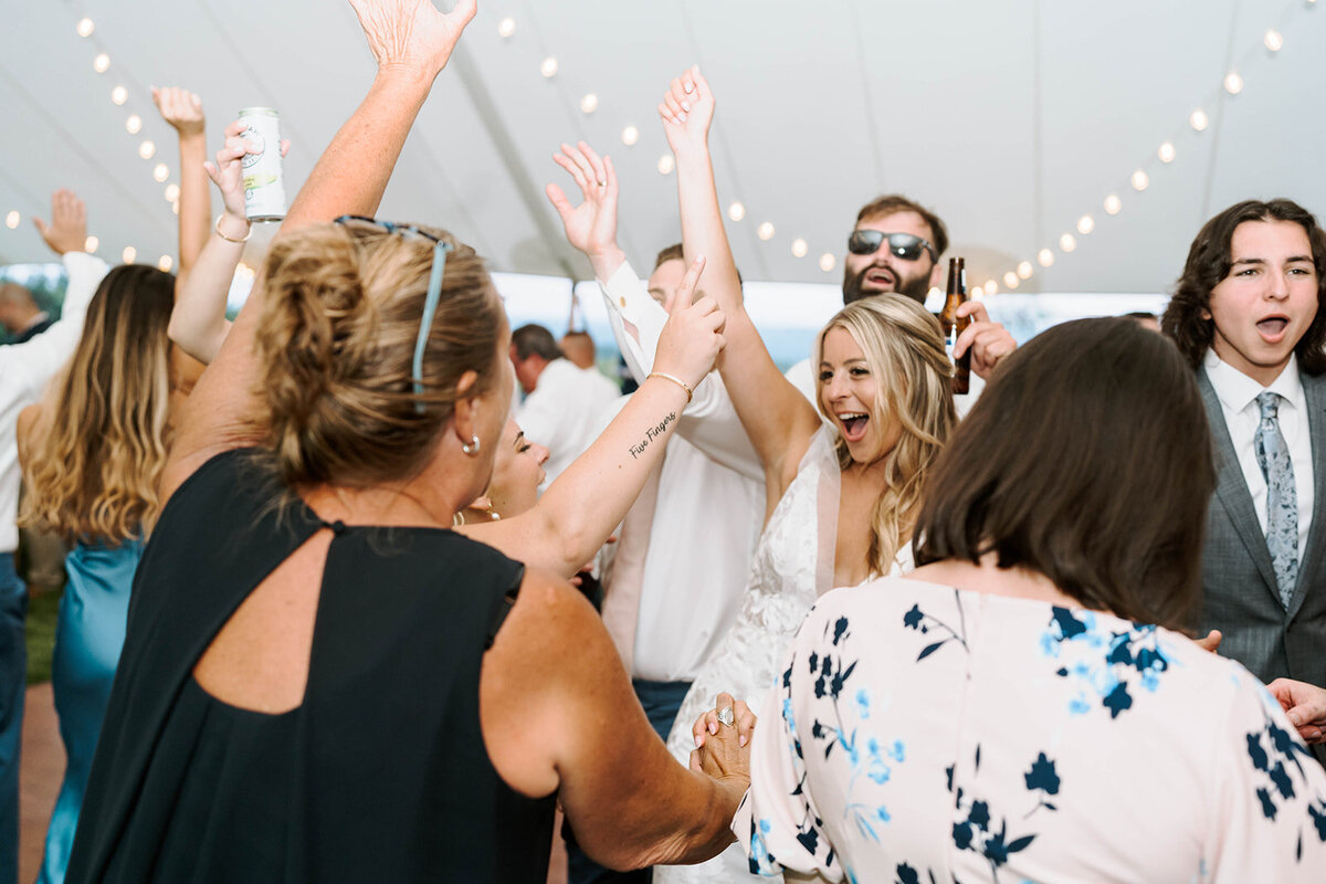 wedding guests dancing with hands up under sailcloth tent in upstate new york venue