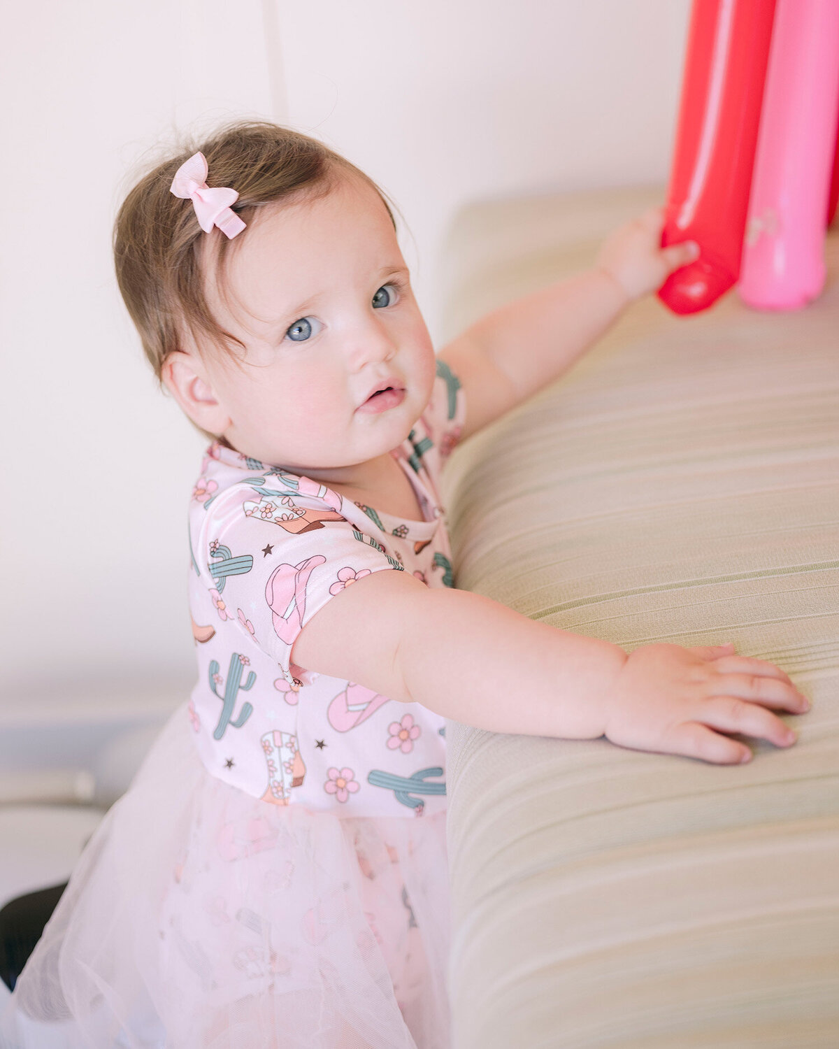 Portrait of chubby baby girl wearing a pink outfit at her first birthday party in the San Francisco Bay Area, captured by a first birthday party photographer.