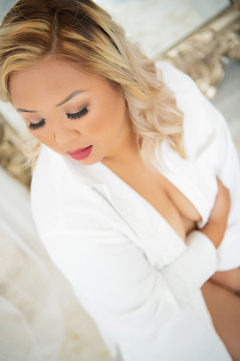 A stunning portrait of a woman in a classic white dress shirt, showcasing her sophistication and confidence in a timeless and elegant way. Captured in a boudoir setting, this image exudes beauty and poise, perfect for anyone looking for a timeless and sophisticated boudoir experience.