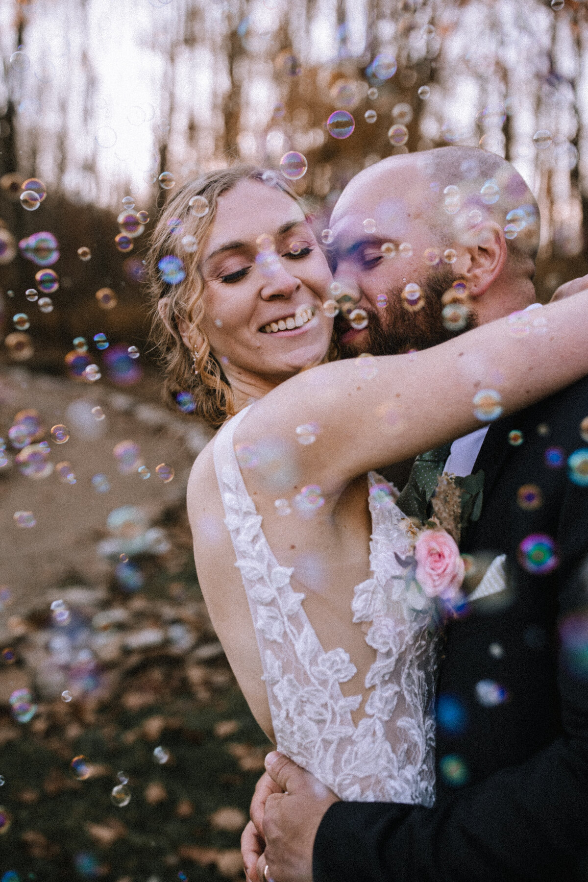 Groom kissing a bride with bubbles blowing around them. 