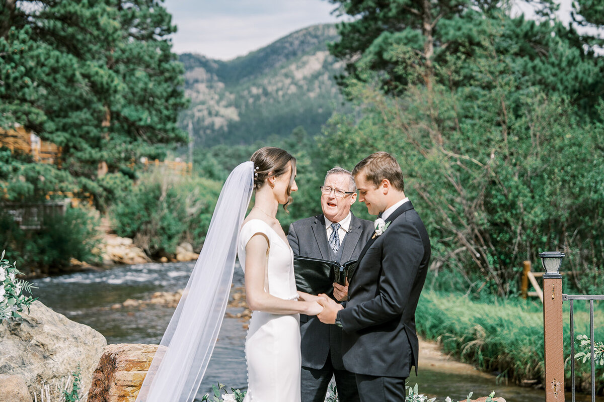 Wedding ceremony in the Colorado mountain with a bride and groom  reading their vows at the Landing in Estes Park.