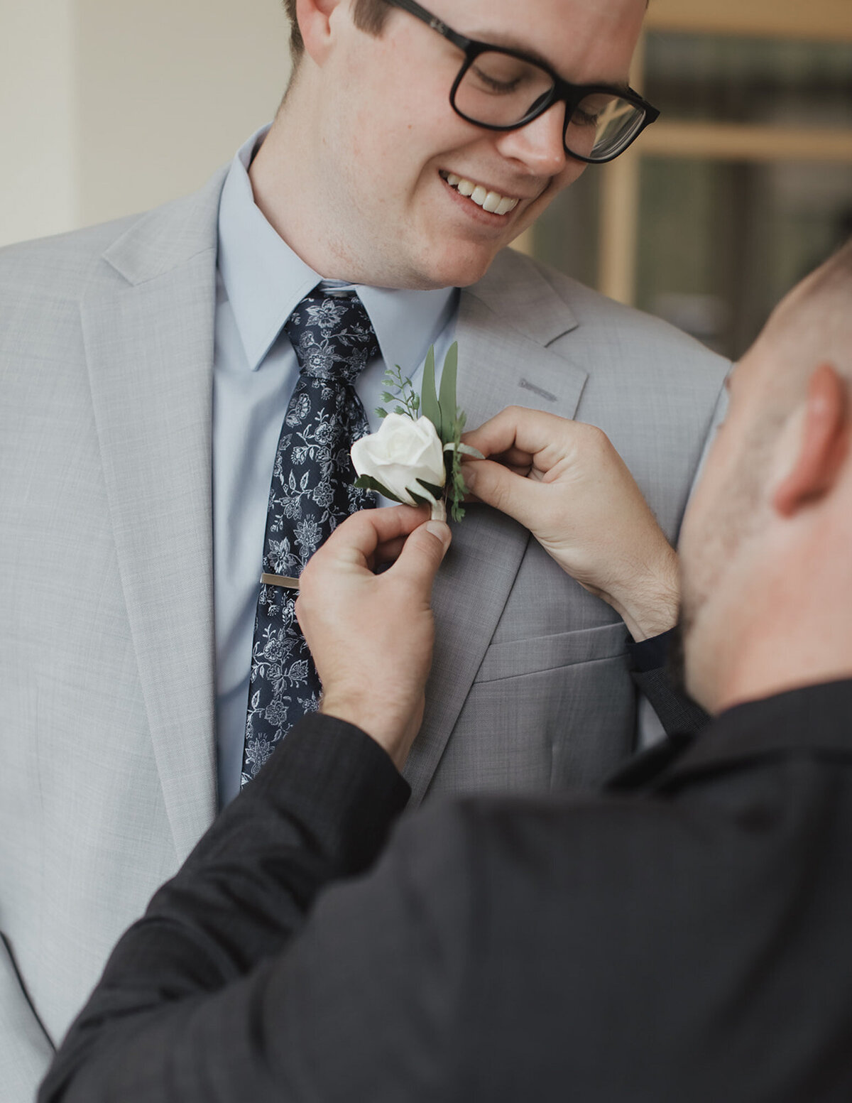 Groom's Best Man fixing the grooms' floral pin