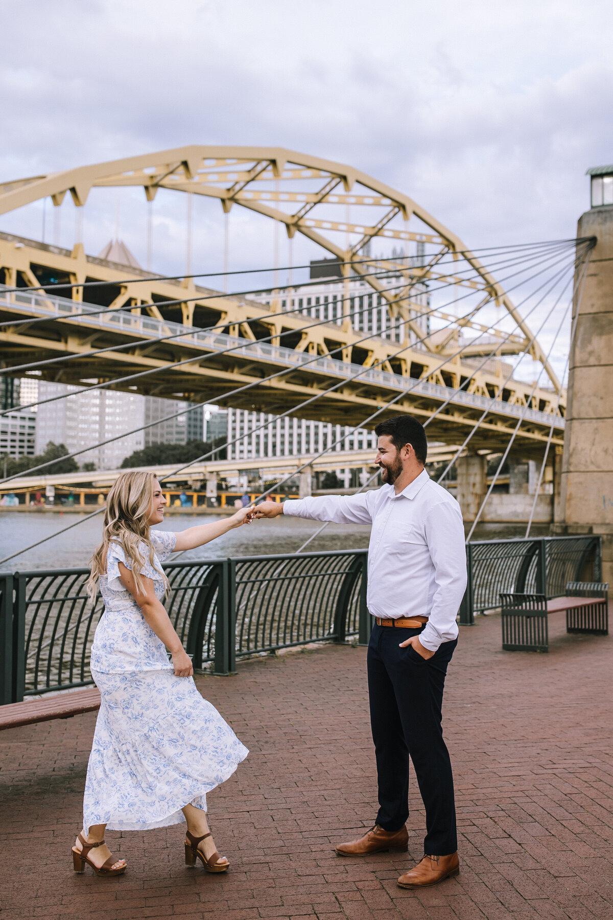 Engaged couple on the north shore of Pittsburgh by the yellow bridges.