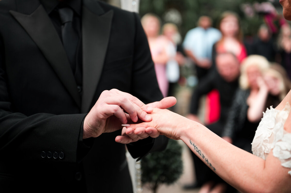 candid moment of groom placing the wedding band on his brides finger
