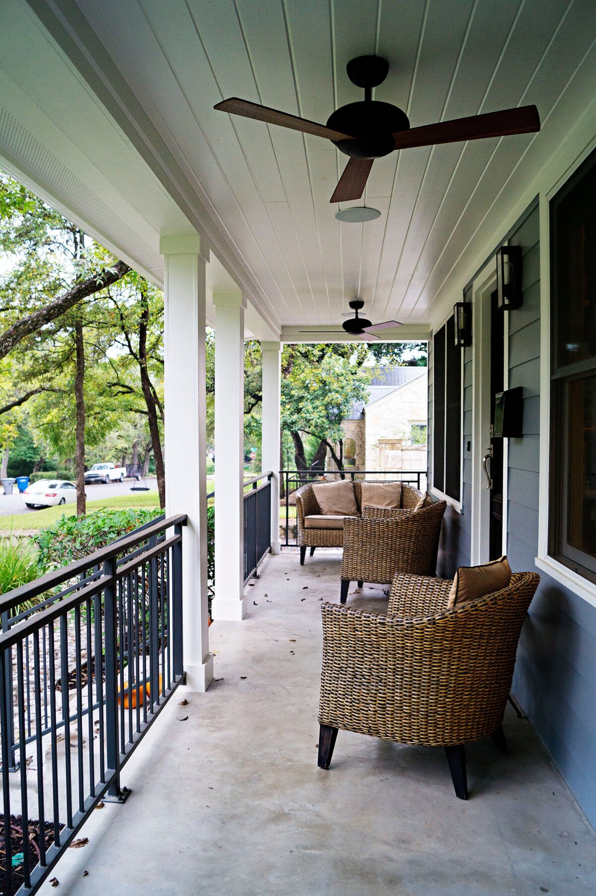 Long front porch with furniture. Wicker patio furniture for modern home.