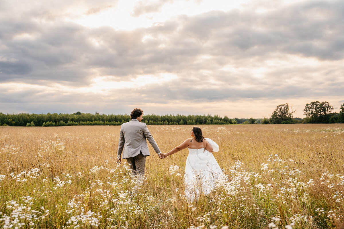 Bride and groom holding hands in Minneapolis field - Kelly Friday Photography 