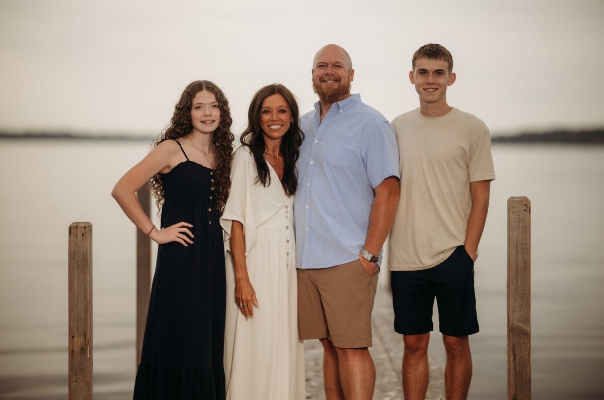 Kenzie Mosher smiling with her husband and two kids, representing her motivation behind helping women prioritize health and balance family life.