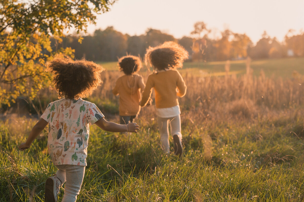 boston family photo of kids running through field at sunset