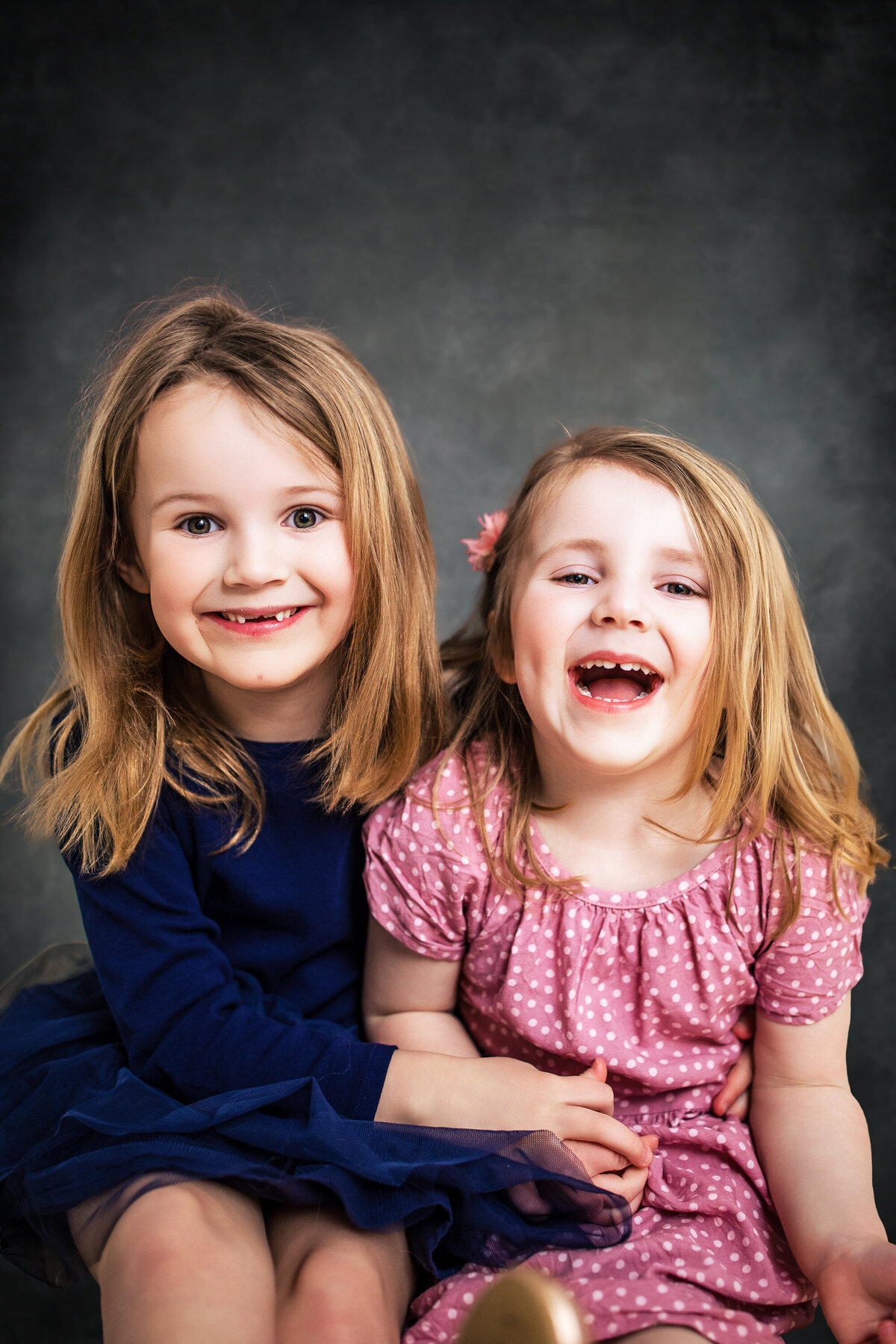 Sisters embrace and laugh at the camera during a portrait session at the Pittsburgh photography studio