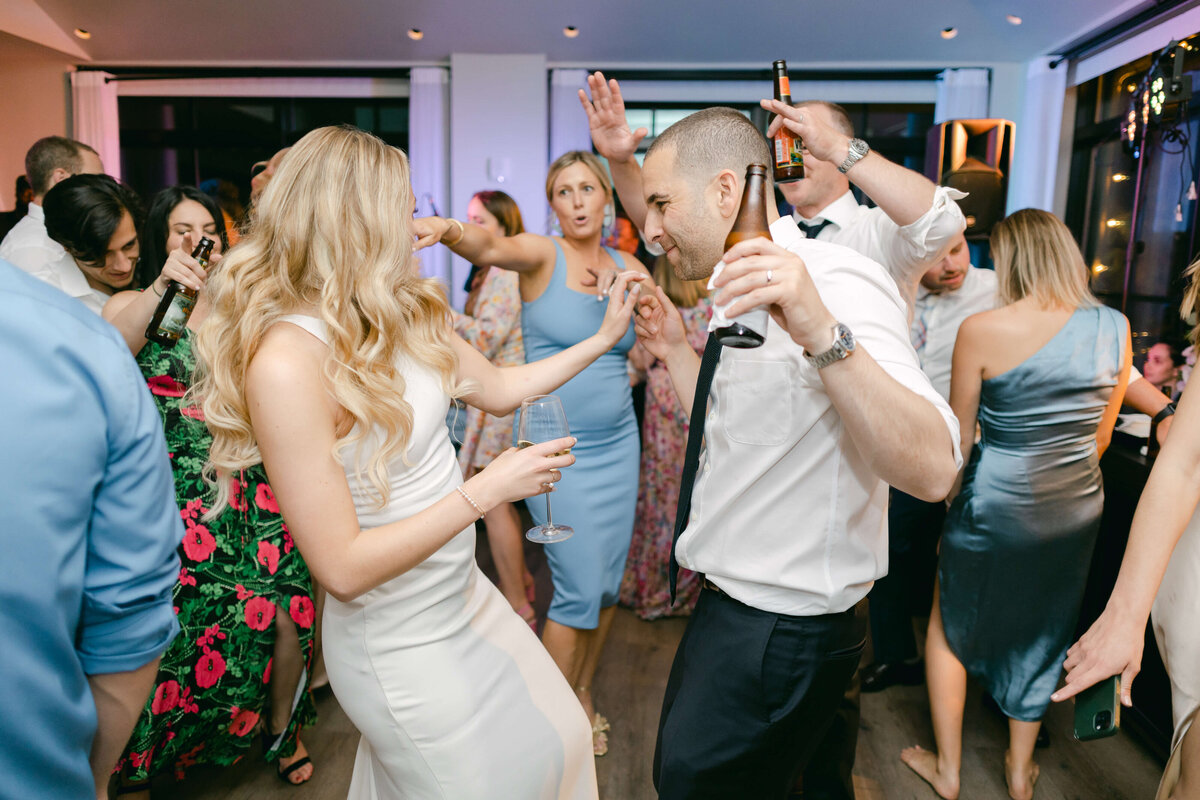 A bride and groom dance while holding drinks.