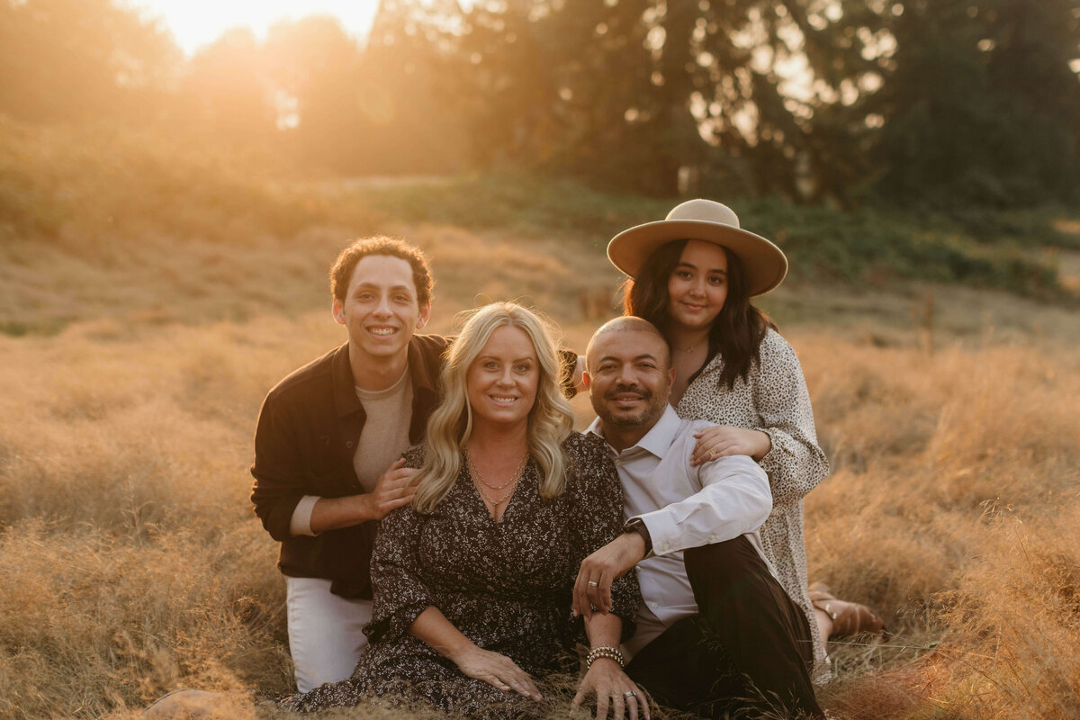 Family sitting down in a field with golden sun