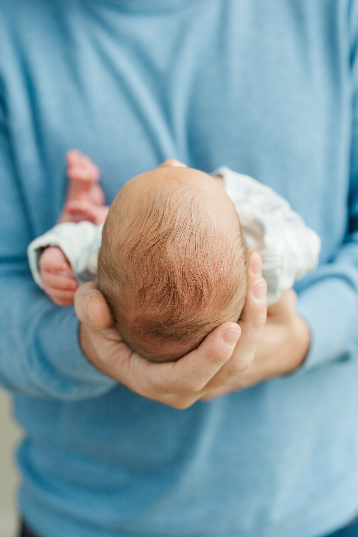 Father cradling his newborn baby in his arms, gazing down with love and tenderness