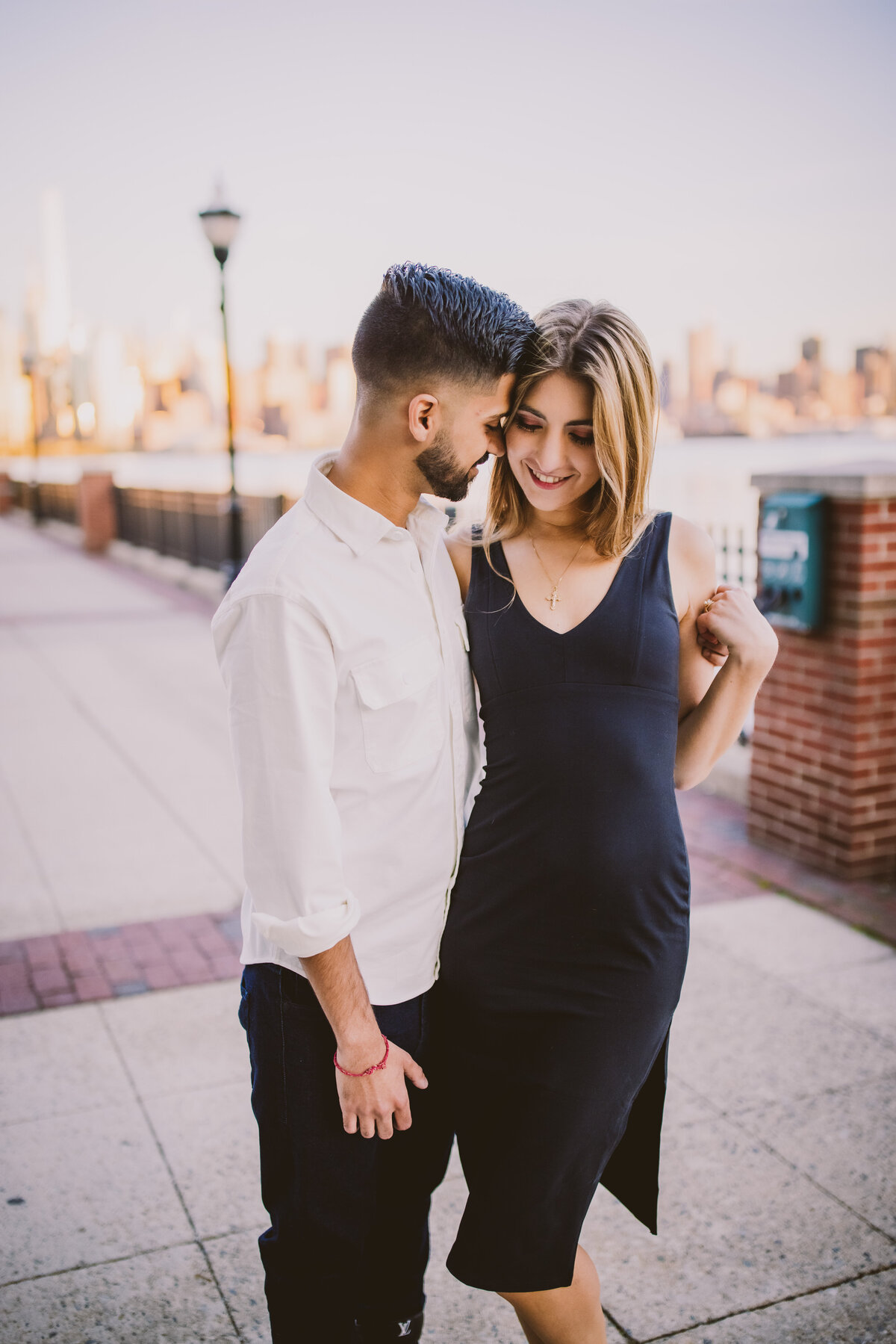 An engaged couple sharing a moment at the riverwalk view nyc in west ny in nj