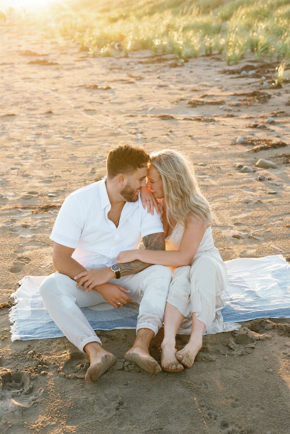 Couple sitting together at the beach for their summer engagement session