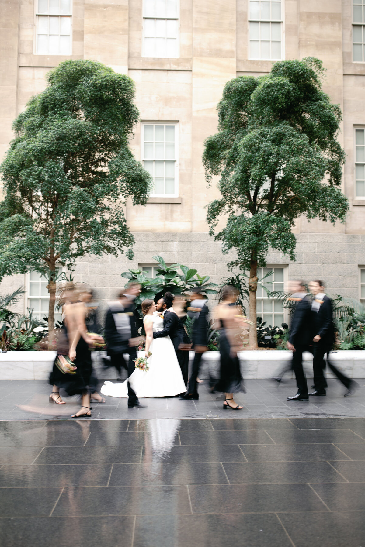 A bridal party walks through the National Portrait gallery in black tie attire after the wedding ceremony in Washington DC