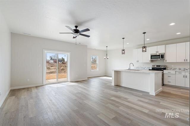 empty living room space with light wood floors glass patio door and ceiling fan