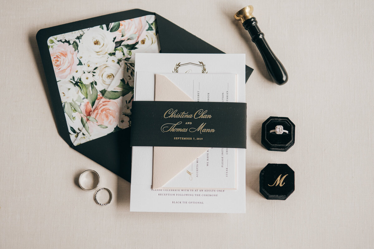 Glamorous black, gold, and floral wedding invitations and wedding bands