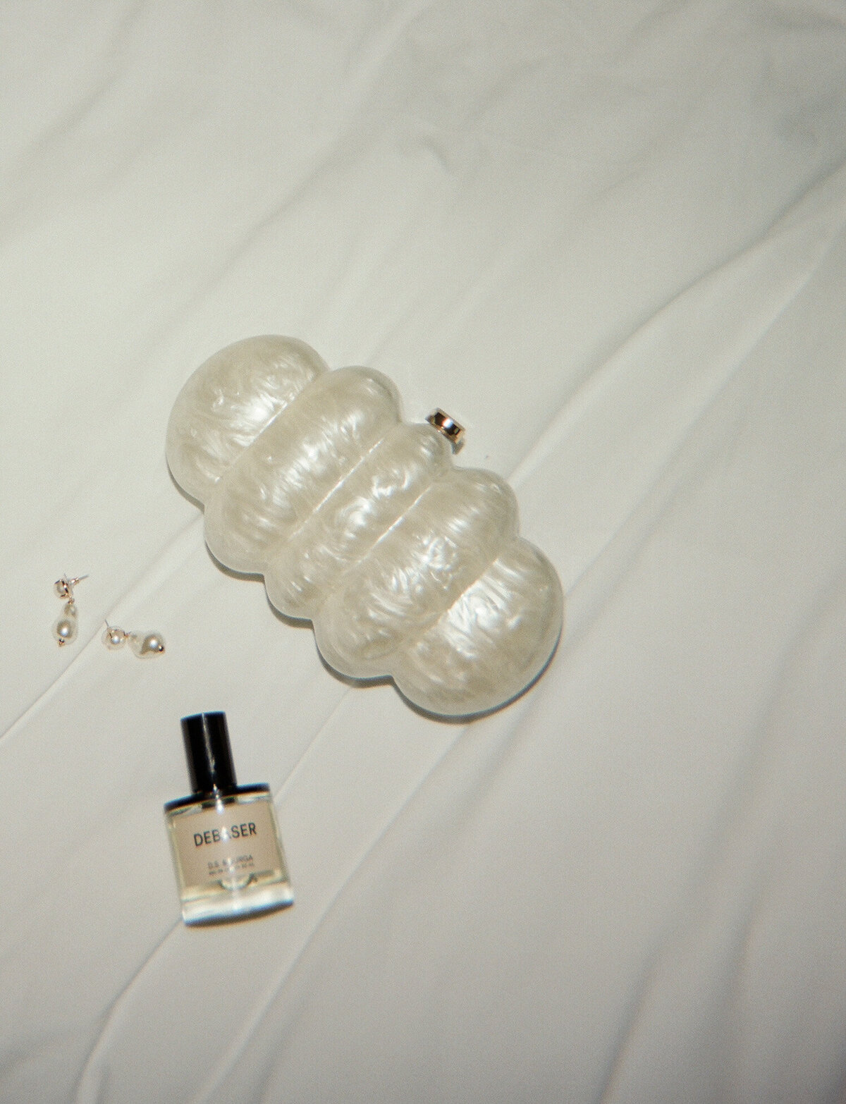 film wedding detail photography of perfume, baroque pearl wedding earrings, pearly clutch at Shinola Hotel