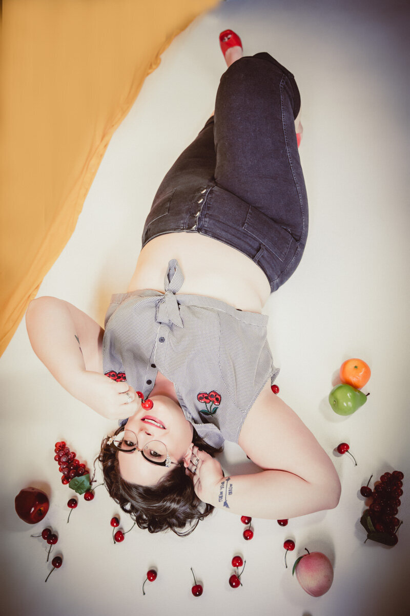Woman with glasses laying on floor in Minneapolis  with fruit all around her and pinup hair