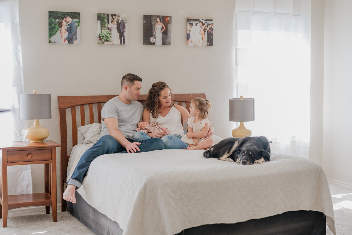 Family with a newborn relaxes in the master bedroom during San Antonio newborn pictures.