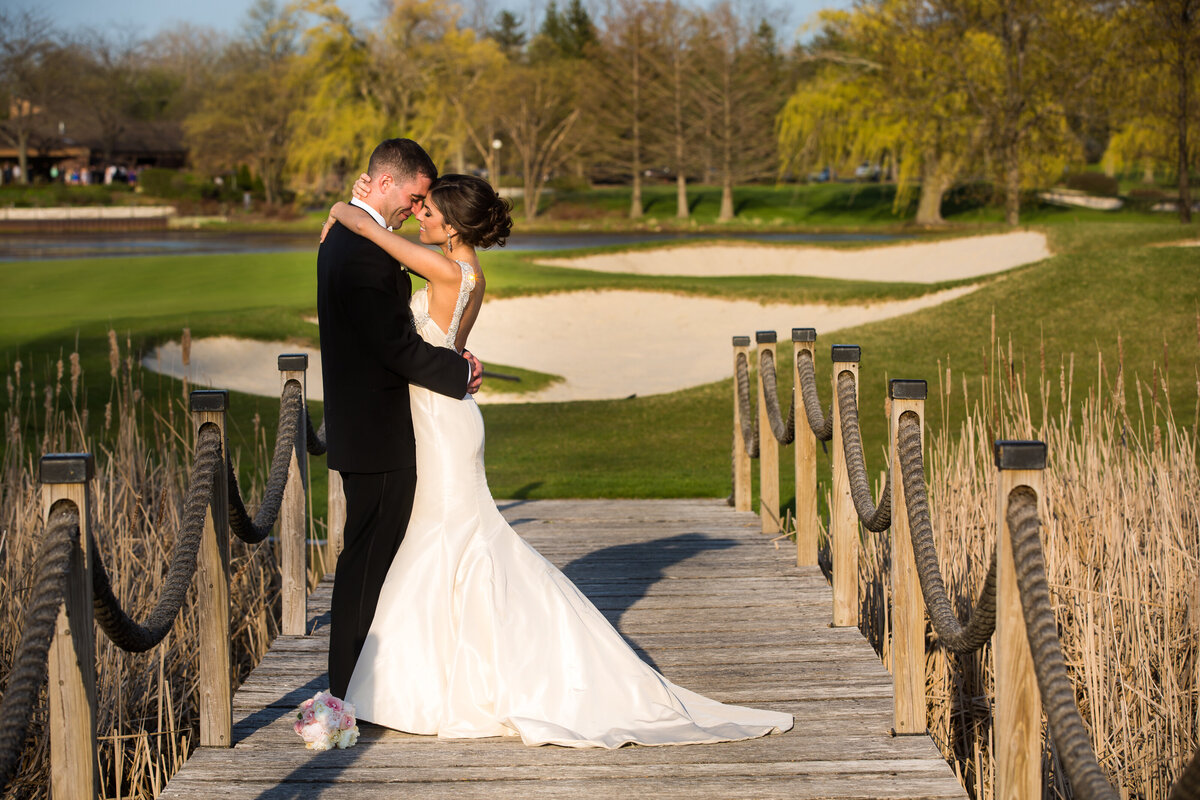 An outdoor wedding photo on a golf course bridge.